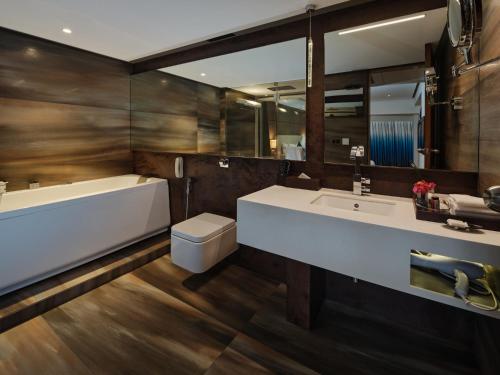 a bathroom with a sink and a tub and a toilet at Sayaji Indore in Indore