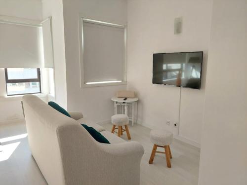 a white living room with a couch and a tv at Aveiro Home in Aveiro