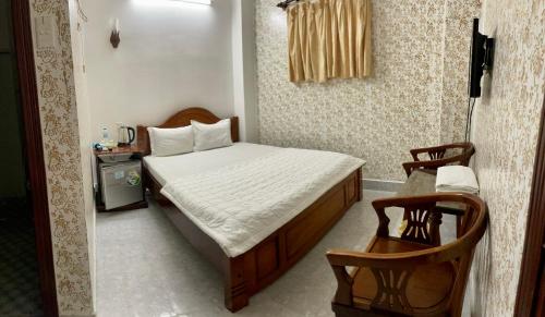 a small bedroom with a bed and two chairs at Thuy Van Hotel in Vung Tau
