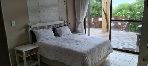 a bedroom with a bed and a door to a porch at Kangela 8A in Ponta Malongane