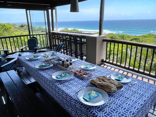 a table with plates of food on a balcony with the ocean at Kangela 8A in Ponta Malongane