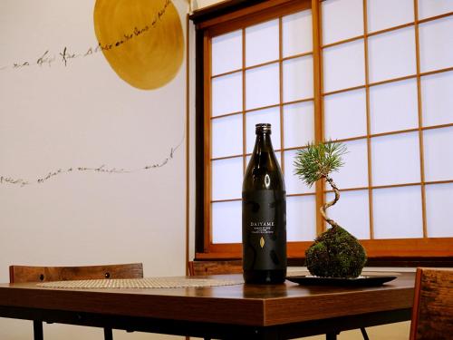 a bottle of wine sitting on a table with a plant at ゆいまーるEAST - Yuimaru East in Kanazawa