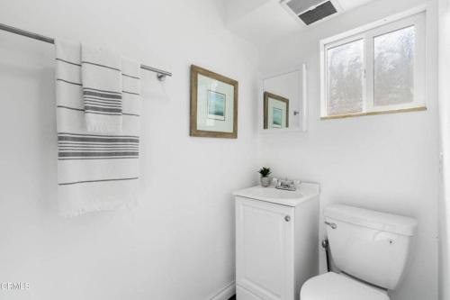 een badkamer met een toilet en twee foto's aan de muur bij Modern 4 King Beds, Beautiful Large Backyard, Golf, WFH, Long Stays, WI-FI, FWY, 25 mins to Beach in Casa Conejo