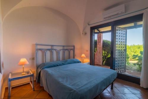 um quarto com uma cama azul e uma grande janela em Villa Baia - Porto Rafael em Palau