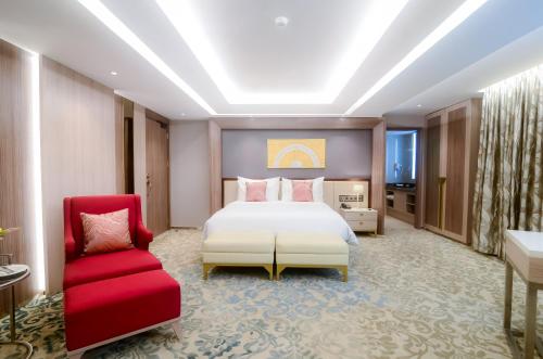 1 dormitorio con 1 cama y 1 silla roja en The Excelton Hotel, en Palembang