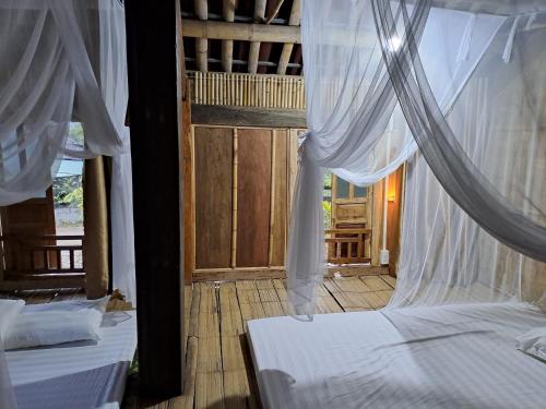 two beds in a room with white drapes at Muong Bi Homestay - Uncle Lon - Luy Ai village in Hòa Bình
