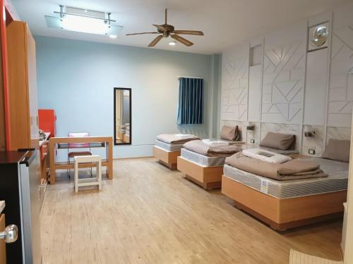 a room with three beds and a table and a ceiling fan at 97 Merryland Apartments & Hotel in Ban Bang Samak