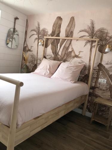 - une chambre avec un lit à baldaquin et des palmiers sur le mur dans l'établissement Face à la mer, bel appartement, à Saint-Nazaire