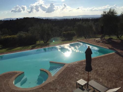 una persona parada frente a una piscina en Rododendro casa sulle colline Toscane vicino San Giminiano en Castelfalfi