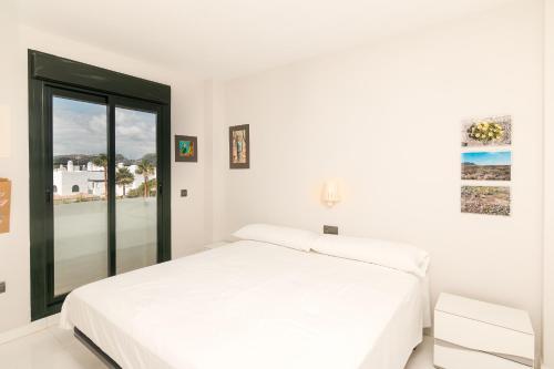 a white bedroom with a white bed and a window at 2207-Modern apt with terrace and amazing seaview in Casares