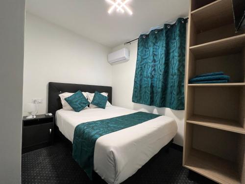 Un pequeño dormitorio con una cama con cortinas azules en HOTEL DE LA PAIX Lyon Sud Givors en Givors