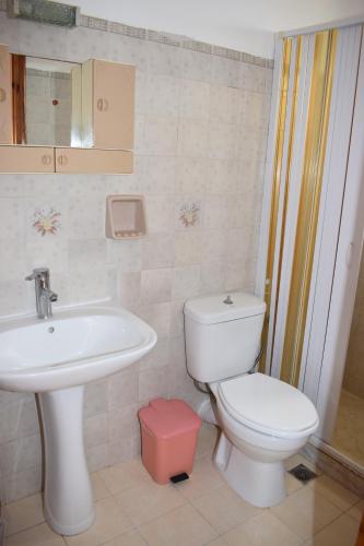 a bathroom with a white toilet and a sink at SUNSET BAY STUDIOS in Agios Georgios