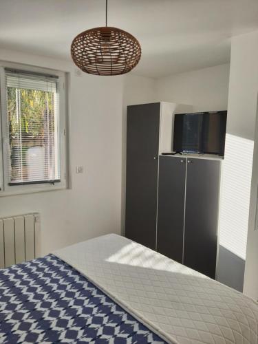 1 dormitorio con 1 cama, armario y TV en Appartement Pérols Centre en Pérols