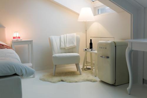 a white room with a chair and a refrigerator at B&B De Kloostertuin in Middelburg