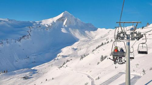 a ski lift with people on a snow covered mountain at Faschina Apartment - Top 1 in Fontanella