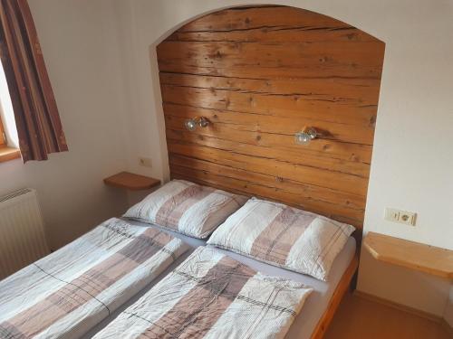 uma cama num quarto com uma parede de madeira em BIO Bauernhof GEISL em Sankt Ulrich am Pillersee