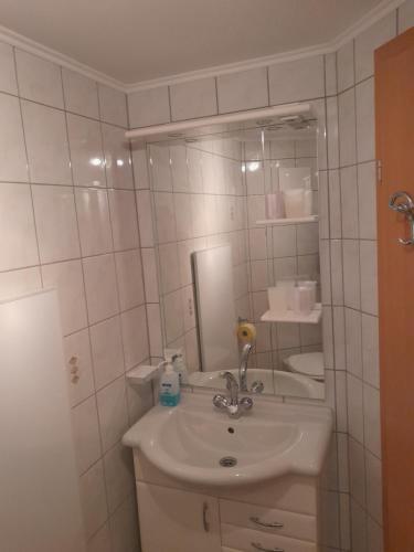 uma casa de banho branca com um lavatório e um espelho em BIO Bauernhof GEISL em Sankt Ulrich am Pillersee
