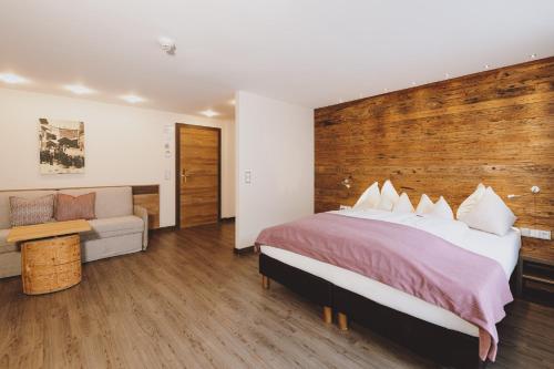 a bedroom with a large bed and a couch at Hotel DIE SONNE in Saalbach Hinterglemm