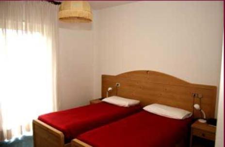 a red bed in a room with a window at Hotel Florida in Levico Terme
