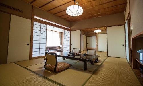 a room with a table and chairs in a room at Sakahijiri gyokushoen in Izu