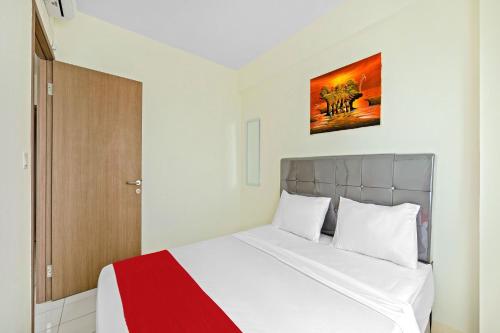 een slaapkamer met een bed met een rode en witte deken bij Skyland Podomoro Golf View Apartemen in Bogor