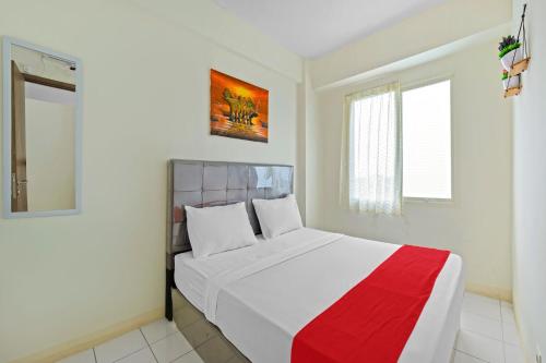 een slaapkamer met een wit bed en een rode deken bij Skyland Podomoro Golf View Apartemen in Bogor