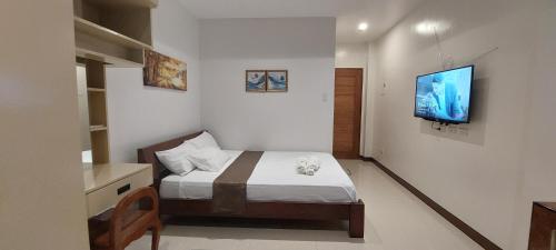 um quarto com uma cama e uma televisão na parede em Le Chateau Residences em Bacolod
