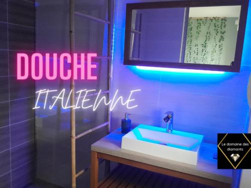a bathroom with a sink and a neon sign at Fraisier, hotel artres - valenciennes in Quérénaing