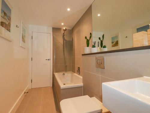 a bathroom with a sink and a toilet and a shower at Fistral Retreat in Newquay
