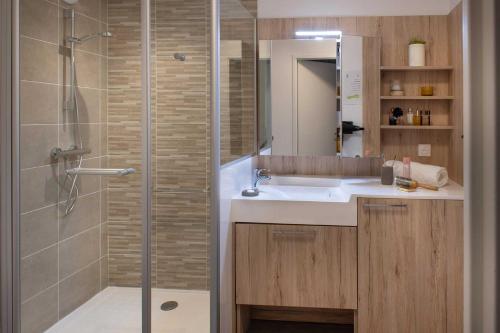 uma casa de banho com um chuveiro com um lavatório e um chuveiro em Domitys Le Domaine d'Agate em Soissons