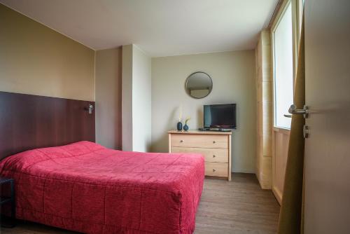 a bedroom with a red bed and a television at Les Jardins de l'Anjou in La Pommeraye