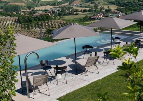 a group of tables and chairs with umbrellas next to a pool at Ca' del Profeta Relais & Spa in Montegrosso dʼAsti