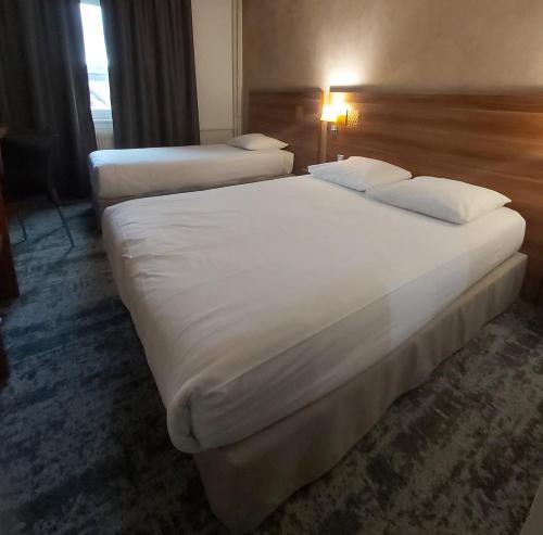 two beds in a hotel room with white sheets and pillows at The Originals City, Hôtel Colmar Gare in Colmar