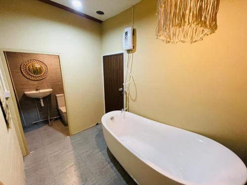 a bathroom with a bath tub and a sink at U're Holitel in Haad Rin