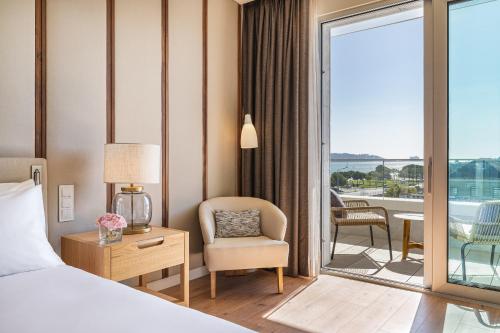 a hotel room with a bed and a chair and a balcony at Hyatt Regency Lisbon in Lisbon