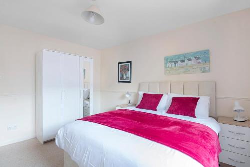 een witte slaapkamer met een groot bed met een rode deken bij Elegance Graceland in Gillingham