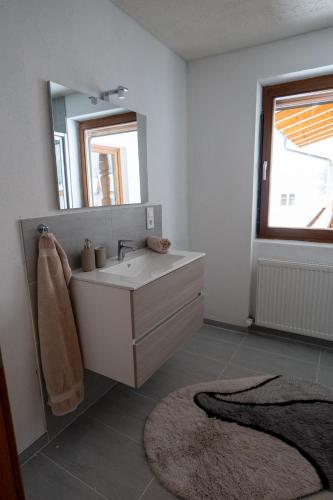 a bathroom with a sink and a mirror and a rug at Haus Kappeller in Bach