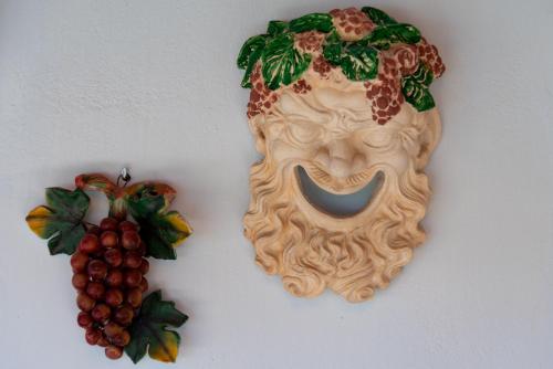 a mask and a bunch of grapes on a wall at Posidonia Luxury Villas Kolympia in Kolimbia