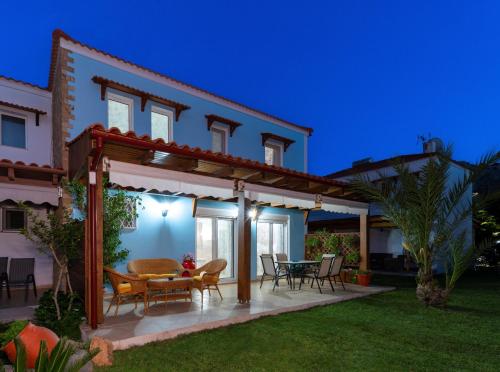 a patio of a house with a table and chairs at Posidonia Luxury Villas Kolympia in Kolimbia