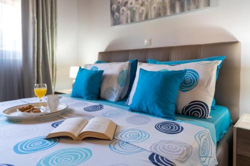 a bed with two books and a plate of food on it at Posidonia Luxury Villas Kolympia in Kolimbia