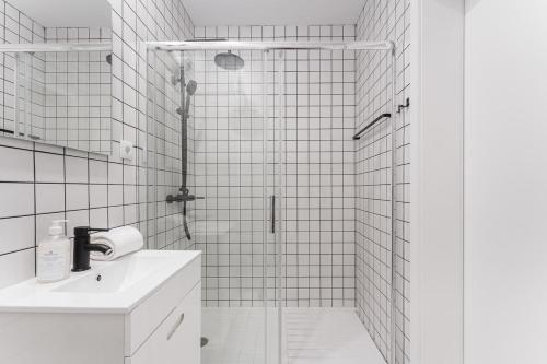 a white tiled bathroom with a shower and a sink at GuestReady - Uptown suites in Porto