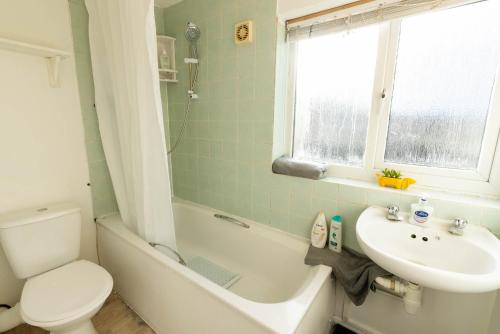 a bathroom with a sink and a toilet and a bath tub at 3 Bedroom house with free parking, Dalstone,Aylesbury in Buckinghamshire