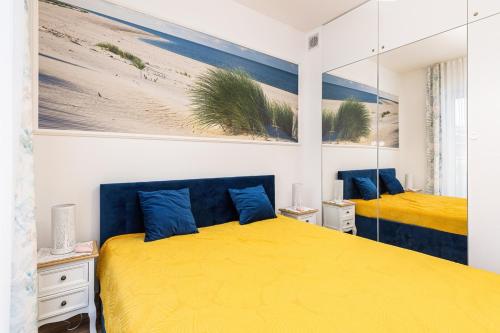 um quarto com 2 camas com lençóis amarelos e almofadas azuis em Apartament Holiday 8/25 em Rewal