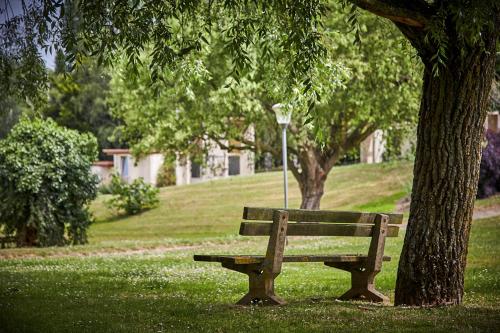 a park bench sitting under a tree in a park at Les Jardins de l'Anjou in La Pommeraye