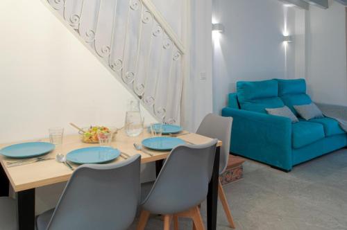 a dining room with a table and a blue couch at ABAL Apartments - Barrio in Alicante