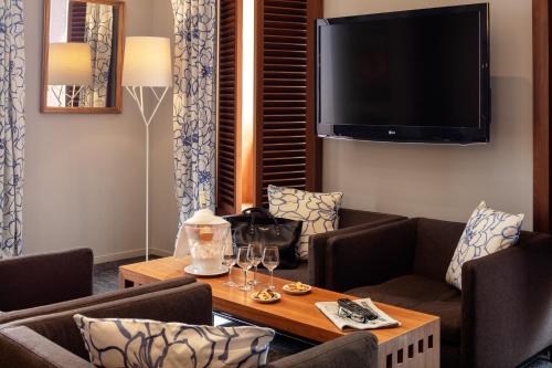 a living room with a table and chairs and a tv at Hotel Beau Rivage in Nice