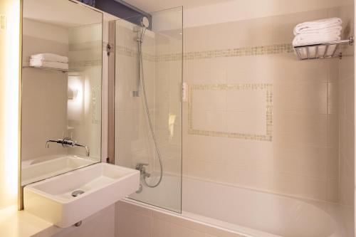 a bathroom with a sink and a glass shower at Hotel Beau Rivage in Nice
