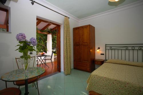 ein Schlafzimmer mit einem Bett und einem Tisch mit einer Blumenvase in der Unterkunft Residence Hotel Villa Fiorentino in Lipari