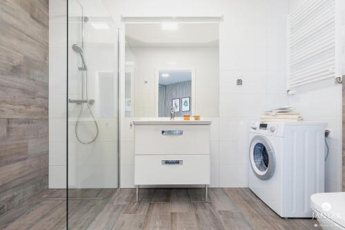 biała łazienka z pralką i pralką w obiekcie Jantar Apartamenty - Boutique Polanki Park SPA w Kołobrzegu