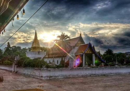 a temple with the sun setting in the background at ทุ่งยั้งเฮ้าส์ in Uttaradit